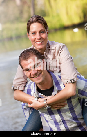 Wunderschönes junges Paar, das Spaß bei einer Huckepack-Fahrt im Park hat Stockfoto