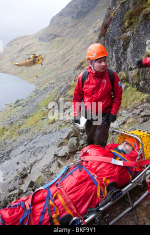 Ein Spaziergänger mit einer zusammengesetzten Bein Fraktur wird von Langdale/Ambleside Bergrettung auf Pavey Arche im Lake District behandelt. Stockfoto