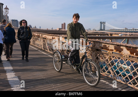 New York, NY - April 2010-Mann reitet ein Dreirad Erwachsene-Dienstprogramm auf dem Gehweg von der Brooklyn Bridge. Stockfoto