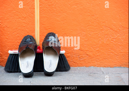 Schuhe auf Besen vor bunt bemalte orange Haus in Burano in der Nähe von Venedig Italien Stockfoto