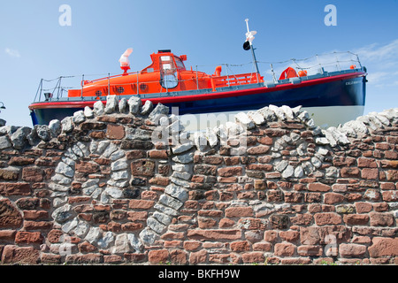 Eine alte Rettungsboot und einer Steinmauer wirken, wie Wellen außerhalb des Dock-Museums in Barrow in Furness, Cumbria, UK Stockfoto