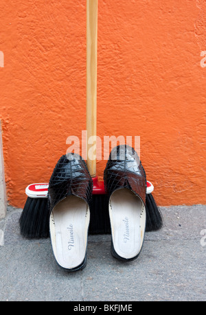 Detail der Schuhe ruht auf Besen vor bunten orange Haus in Burano in der Nähe von Venedig Italien Stockfoto