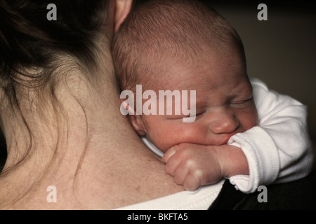 Über die Schulter-Foto von einer Mutter hält liebevoll ein neugeborenes Baby Boy. Das Baby sieht getröstet und Mutter umarmt Stockfoto