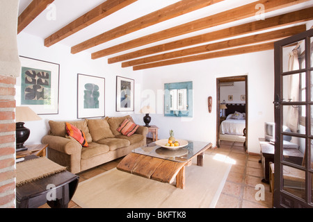 Im Holzbalken spanische Wohnzimmer mit rustikaler Couchtisch aus Holz und Creme Teppich Beige Velour sofa Stockfoto