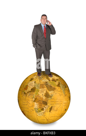 Ein internationaler Geschäftsmann, stehend auf einem Globussymbol während des Gesprächs auf seinem Handy. Stockfoto