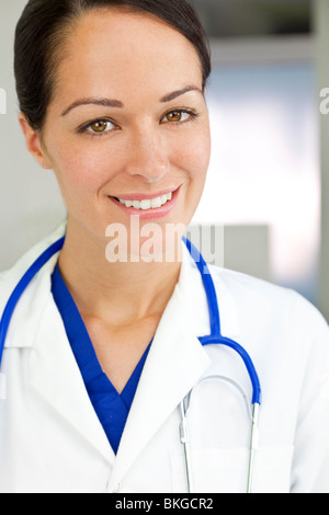 Ein attraktives Lächeln Ärztin trägt einen weißen Kittel und Stethoskop in einem Krankenhaus. Stockfoto