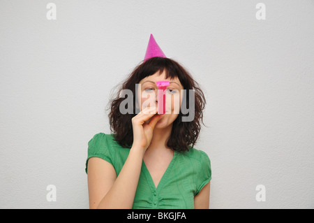 Junge Frau bläst Lärm Gebläse Stockfoto