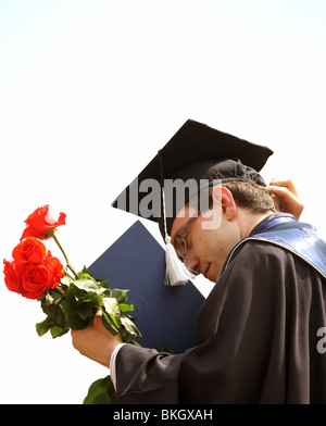 Student mit roten Rosen nach seiner Abschlussfeier Stockfoto