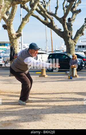 Cannes, La Croisette, alten Mann im Baseball-Cap wirft Ball spielen Boule oder Boccia mit Marina im Hintergrund Stockfoto