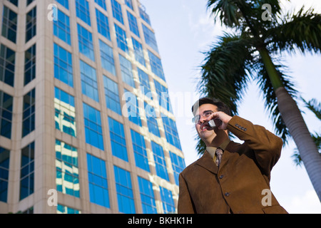 Geschäftsmann Stand durch hohes Gebäude am Handy auf der Straße sprechen. Fort Lauderdale, Florida, USA Stockfoto