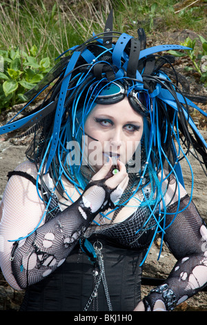 Junge Goth-Frau (MR), die am 2010. April auf dem Whitby Goth Festival in Yorkshire, Großbritannien, einen blauen Lippenstift ansetzt und Plastikgürtel als Haarschmuck trägt Stockfoto