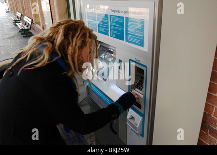 Junge Frau mit Dreadlocks Kauf von Bahntickets aus den Automaten am Bahnhof Aberystwyth, Wales. Stockfoto