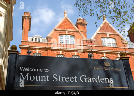 Willkommen Sie Schild am Mount street Gardens, Mayfair, London, England, mit rosa Terracotta Gebäude im Hintergrund Stockfoto