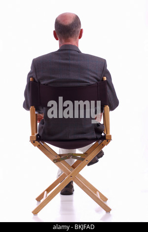 Rückansicht des elegant gekleidet reifen Mann sitzen in einem Regiestuhl. Isoliert. Stockfoto