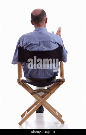 Rückansicht des elegant gekleidet reifen Mann sitzen in einem Regiestuhl. Isoliert. Stockfoto
