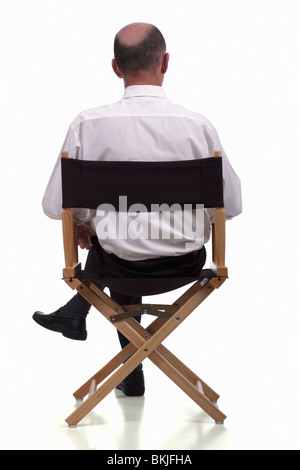 Rückansicht des elegant gekleidet reifen Mann sitzen in einem Regiestuhl. Isoliert. Stockfoto