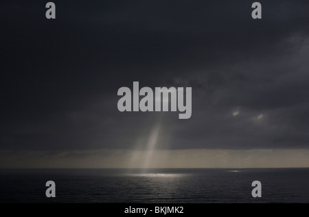 Eine Welle der Sonne durch die Wolken nach einem Sturm über dem Meer in Neuseeland Stockfoto