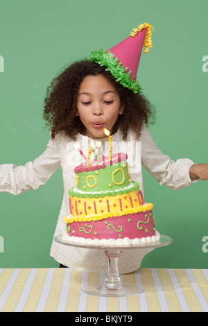 Mädchen mit Geburtstagskuchen, Kerzen ausblasen Stockfoto