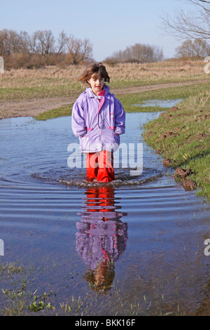 Porträt eines jungen Mädchens zu Fuß durch eine Pfütze Stockfoto