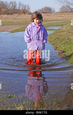 Porträt eines jungen Mädchens zu Fuß durch eine Pfütze Stockfoto
