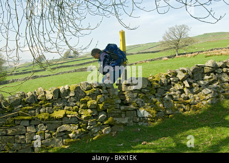 Walker, überqueren einen Stil in einer Trockensteinmauer vom Fluss South Tyne in der Nähe von Garrigill, Alston, Cumbria, England, UK Stockfoto