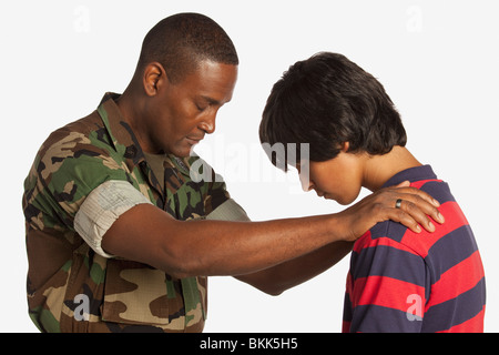 Ein Mann des Militärs für einen Teenager zu beten Stockfoto