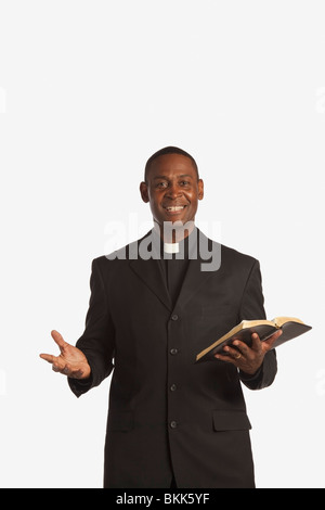 Ein Mann trägt eine klerikal-Kragen und hält eine Bibel Stockfoto
