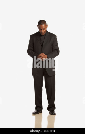Ein Mann mit einem klerikalen Kragen mit im Gebet gesenktem Kopf Stockfoto