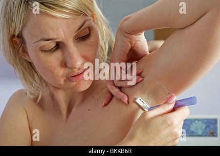Frau rasieren unter den Armen Stockfoto