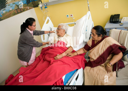 Eine Krankenschwester macht ein Patient bequem im Bett am Klinikum Medicity, Gurgaon Stockfoto