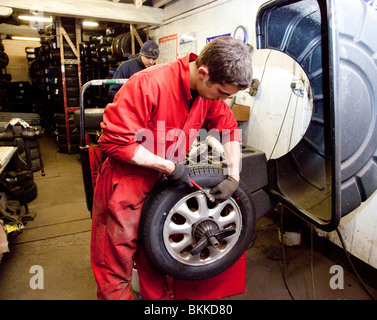 Garage-Arbeiter passend Ausgleichsgewichte an ein Rad Stockfoto