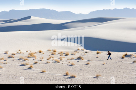Eine Person zu Fuß unter großen weißen Sanddünen in White Sands National Monument, New Mexico. Stockfoto