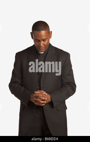 Ein Mann mit einem klerikalen Kragen mit im Gebet gesenktem Kopf Stockfoto
