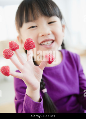 Chinesin mit Himbeeren an Fingern Stockfoto