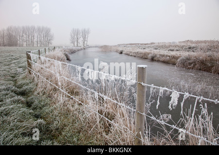 Einen gefrorenen Fluss neben einem Drahtzaun an einem frostigen Morgen Stockfoto