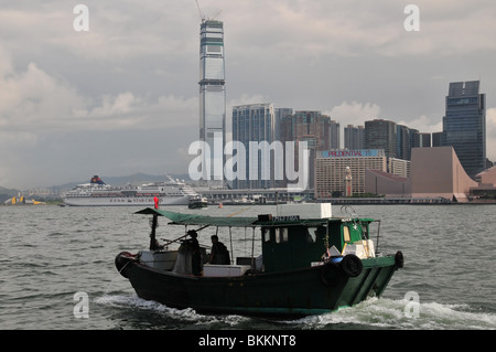 Sampan Fischerboot Bewegung nach Westen durch Victoria Harbour, vorbei an einer Tsim Sha Tsui-Wolkenkratzer-Kulisse, Hong Kong, China Stockfoto