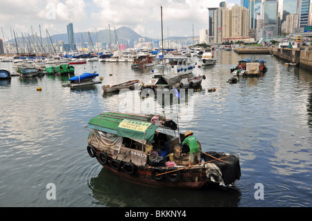 Mann, einen Strohhut tragen auf der Vorderseite ein Sampan-Hausboot in den Gewässern der Causeway Bay Typhoon Shelter, Hong Kong Stockfoto