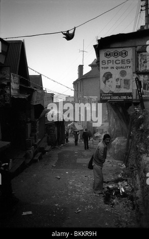 Mit die Sonne noch noch zu steigen einen Mann erwärmt sich durch ein kleines Feuer in Sabzi Mandi, die unteren Bazar in Shimla Stockfoto