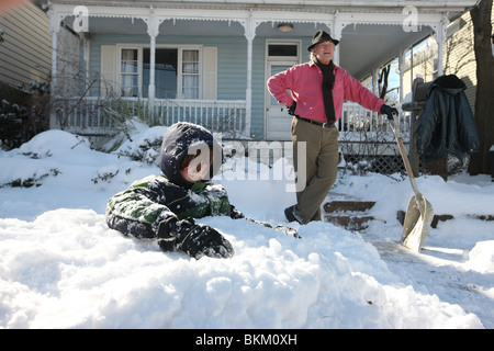 Vater und Sohn genießen Sie einen entspannten Morgen spielen und Schneeschaufeln in Charlottesville, Virginia. Stockfoto