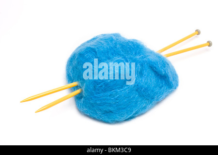 Eine große Kugel aus blaue Mohairwolle durchbohrt mit großen gelben Kunststoff Stricknadeln gegen weiß. Stockfoto