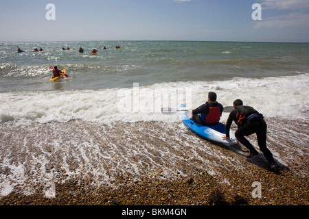 Lehrer von einem Brighton Seafront Kajak Operator schiebt so Meer einen Anfänger. Stockfoto