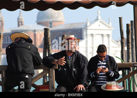 Gondolieri warten auf Touristen in Venedig, Italien. Kirche San Giorgio Maggiore im Hintergrund. Stockfoto