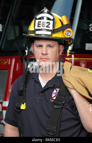 Closeup Feuerwehrmann in seinen Zwanzigern Helm und stand vor Feuerwehrauto Stockfoto