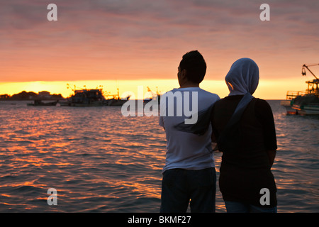 Young-Malay-paar beobachten Sie den Sonnenuntergang am Wasser. Kota Kinabalu, Sabah, Borneo, Malaysia. Stockfoto
