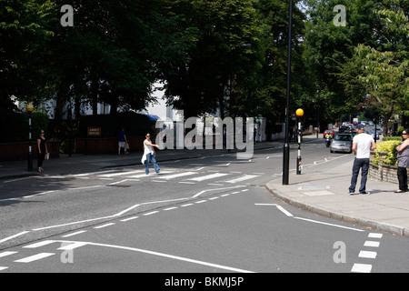 Touristen, die zu Fuß über den berühmten Abbey Road Kreuzung featured auf The Beatles-Album Abbey Road außerhalb des Aufnahmestudios Stockfoto