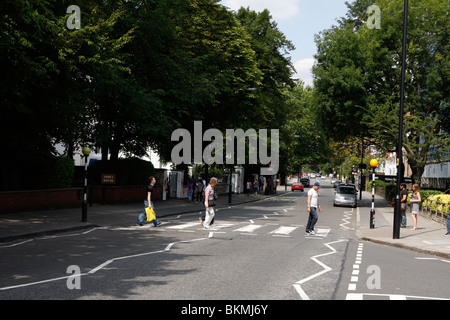 Touristen, die zu Fuß über den berühmten Abbey Road Kreuzung featured auf The Beatles-Album Abbey Road außerhalb des Aufnahmestudios Stockfoto