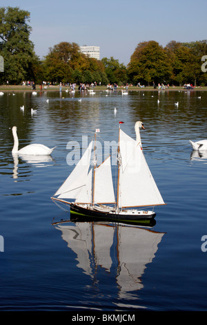 Schwäne und Modellboote auf dem runden Teich in den Kensington Gardens Stockfoto