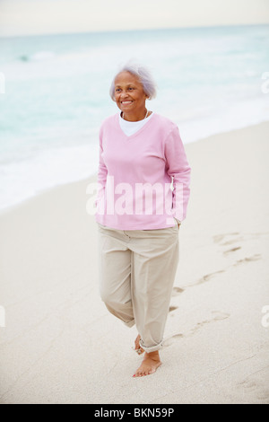 Senior-afroamerikanische Frau zu Fuß am Strand Stockfoto