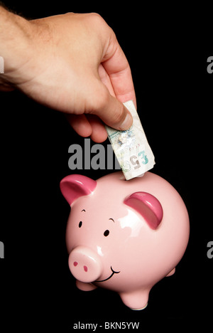 Person spart Geld im Sparschwein Stockfoto