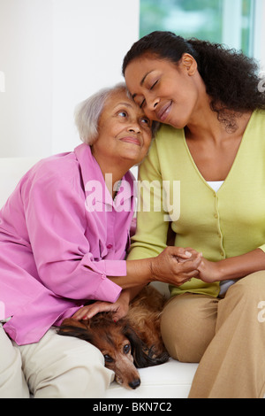 Afroamerikanische Frau sitzend auf Sofa mit Mutter und Hund Stockfoto